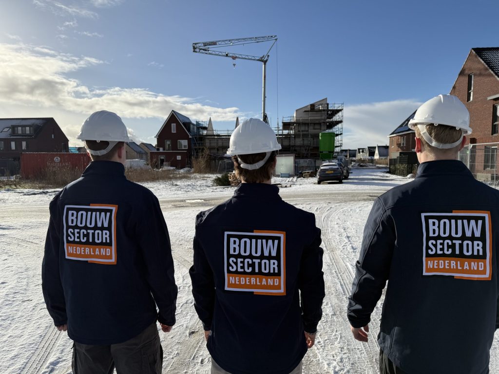 Vakmensen van Bouwsector Nederland in bedrijfskleding kijken uit over een rij huizen